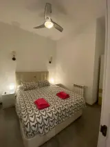 Double bed in the interior apartment under the ceiling fan with radiator and wardrobe in the far right corner